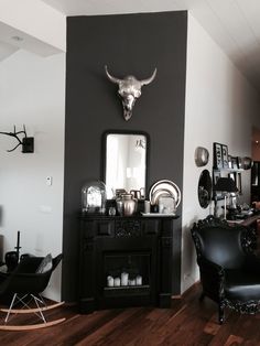 a living room filled with furniture and a cow skull mounted on the wall above a fireplace