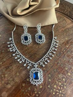 Designer silver diamond jewelry set featuring a stunning necklace with blue diamond accents. This American diamond (CZ) set is perfect for Indian cocktail parties and Pakistani weddings, offering elegance and sophistication. Elevate your collection with this exquisite silver diamond necklace set, ideal for special occasions. Our products are meticulously handcrafted, ensuring each piece is unique. Due to the manual craftsmanship, you may notice slight irregularities, which are natural and do not compromise the quality of the jewelry. Diamond Necklace Set Indian, Blue Diamond Necklace, American Diamond Necklace Set, Princeton Nj, Silver Diamond Jewelry, Diamond Jewelry Set, American Diamond Necklaces, Necklace Set Indian, Silver Diamond Necklace