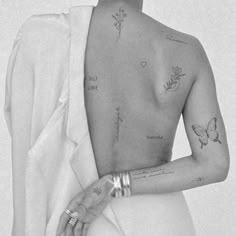 a black and white photo of a woman with tattoos on her back