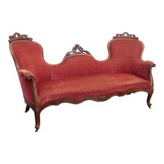 an old fashioned red couch with ornate carvings on the armrests and back rest