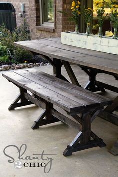 a picnic table with benches and flowers in vases on the back porch outside an apartment building