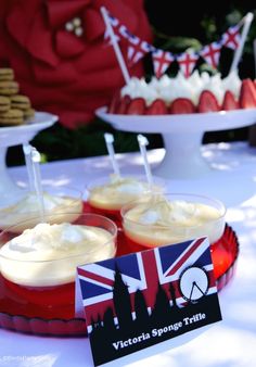 some desserts are sitting on a table with red plates and flags in the background