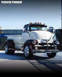 an old white truck parked in front of a fence