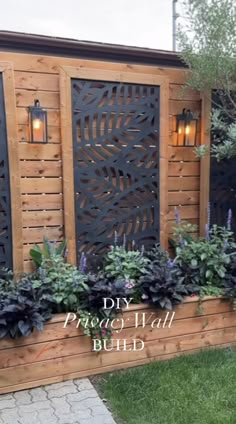 a wooden fence with plants and lights on it in front of a building that says diy privacy wall build