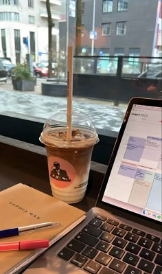 an open laptop computer sitting on top of a desk next to a cup of coffee