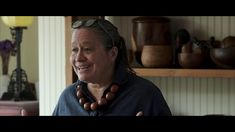 an older man wearing a necklace with wooden beads on it's neck and giving the thumbs up sign