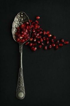 a spoon full of cranberries on top of a black surface with other items