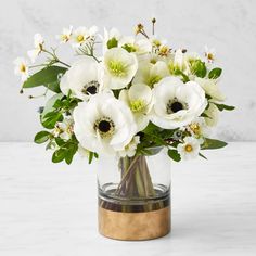 a vase filled with white flowers sitting on top of a marble countertop next to a wall