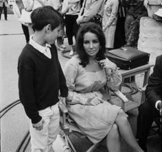 an old photo of a woman sitting on a bench with two young boys standing next to her