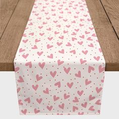 a pink and white table runner with hearts printed on the top, along with polka dots