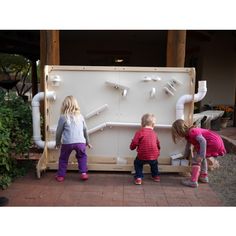 three children are playing in front of a large water fountain that is built into the ground