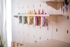 there are many different colored pencils in jars on the wall next to each other