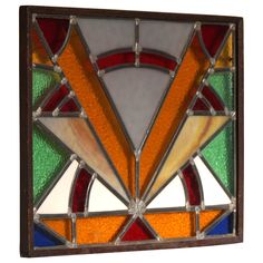 a stained glass window with an orange, green and blue geometric design on it's side