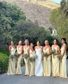 a group of women standing next to each other in front of some trees and bushes