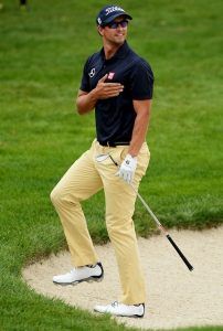 a man holding a golf club on top of a green grass covered field next to a hole