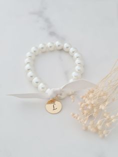 Personalised engraved initial pearl bracelet.  This bracelet features a gold stainless steel initial and ribbon tie in either cream or white. The pearls are available in cream or white and measure 8mm in diameter. This bracelet is stretchy and has no clasp so it can be slipped over the hand. Please see approximate size guide below: Sizes for children 12-24 months    5in 2-3 years    5.0-5.5in 4-5 years    5.75in 6-8 years    6in 9-13 years    6.25in Adult Sizes Small                  6.5in Mediu Bridesmaid Bracelet Flower, Flower Girl Bracelets, Girl Bracelet, Bracelet Flower, Bridesmaid Bracelet, Wedding Jewellery, Gifts Wedding, Ribbon Tie, Pearl Bracelet