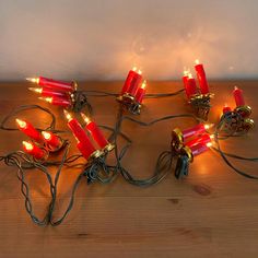 a bunch of red candles that are sitting on a wooden table with some wires attached to them