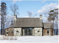 a stone and wood house in the middle of winter with snow on the ground around it