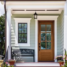 the front door of a house with potted plants and flowers on the steps next to it