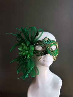 This women's masquerade mask features a rich green base highlighted with intricate gold embellishment and an elegant green floral feather. This mask is the perfect accessory for masquerade parties, balls, Mardi Gras, and other extravagant events! Age Group/Gender - Adult/Women Size/Type - One size fits all adults Mask Color - Green/Gold Mask Material - Polyresin Special Features - Feathers