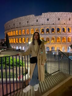 a woman standing in front of the colossion at night with her arms out