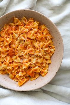 a bowl filled with pasta on top of a white blanket