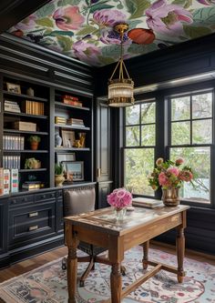 a room with black walls and flowers painted on the ceiling, along with bookshelves