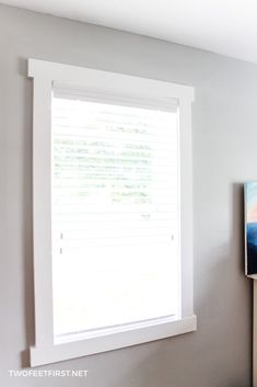 an empty room with a painting on the wall next to a flat screen tv and window