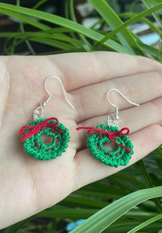 small crochet earrings with red and green yarn on them, sitting in a palm tree