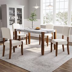 a dining room table with chairs and a rug in front of the table is shown