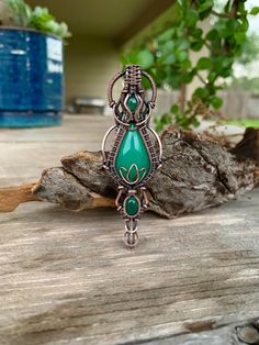 a green pendant sitting on top of a wooden table next to a potted plant