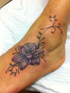 a woman's foot with a purple flower tattoo on the side of her leg