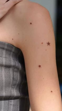 a woman's arm with small stars on her left shoulder and right arm in the background