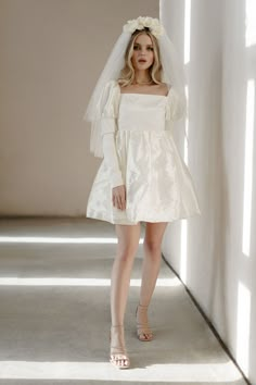 a woman in a white dress and veil posing for the camera with her hands on her hips