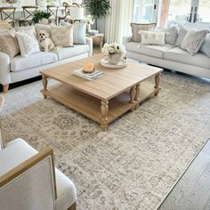 a living room filled with white furniture and lots of pillows on top of it's couches