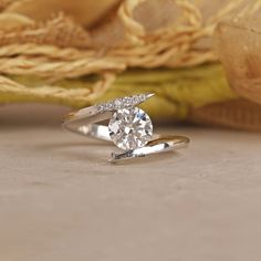 a diamond engagement ring sitting on top of a table next to a yellow and white cloth