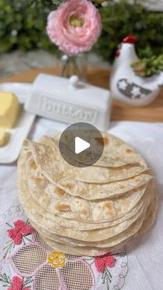 a stack of tortillas sitting on top of a table next to a vase with flowers