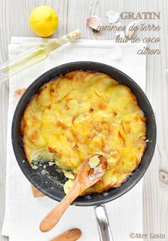 a pan filled with food on top of a white wooden table next to utensils