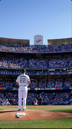 a baseball player standing on top of a field in front of a stadium filled with people