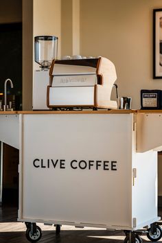 a coffee machine sitting on top of a white cart with the words clive coffee written on it