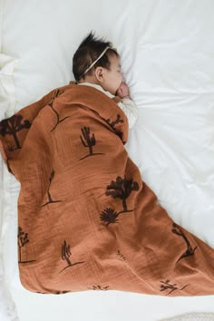 a baby wrapped in a blanket sleeping on a bed