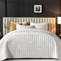 the bed is made with white quilts and pillows