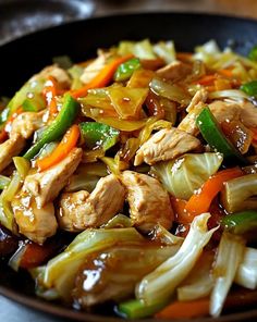 stir fry with chicken, peppers and onions in a black bowl on a table top