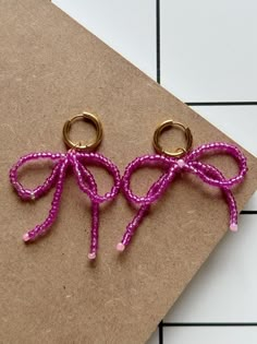 two pairs of pink and gold colored scissors on a piece of brown paper next to a white tile