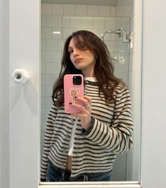 a woman taking a selfie in front of a bathroom mirror with her cell phone