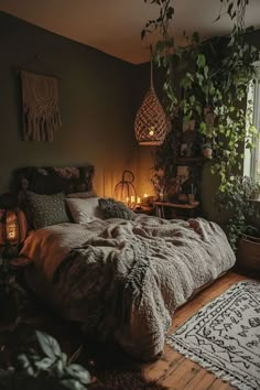 a bed in a bedroom next to a window with candles on the floor and plants hanging over it