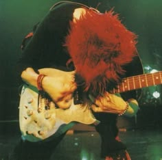 a man with red hair playing an electric guitar