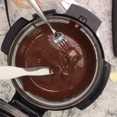 someone using a spatula to mix chocolate in a pot