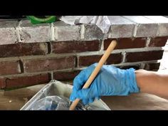 a person in blue gloves and rubber gloves cleaning a brick wall with a plunger