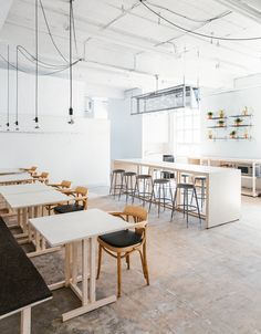 an empty room with tables and stools in it, along with plants on the wall